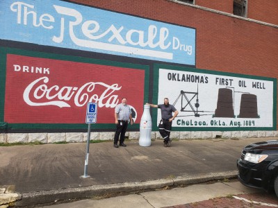 Vinita heroes showing the Recognition Roadtrip bottle at the Chelsea Mural which recognizes Oklahoma’s First Oil Well, in downtown Chelsea, Oklahoma on Oct. 14, 2021.