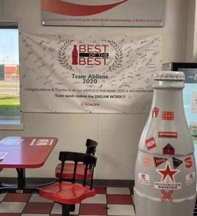 The Recognition Roadtrip Bottle in front of the “2020 Best of the Best” banner on Nov. 8, 2021. Located in the Abilene Distribution Center, this banner signifies the amazing work the Abilene heroes have done over the past two years!