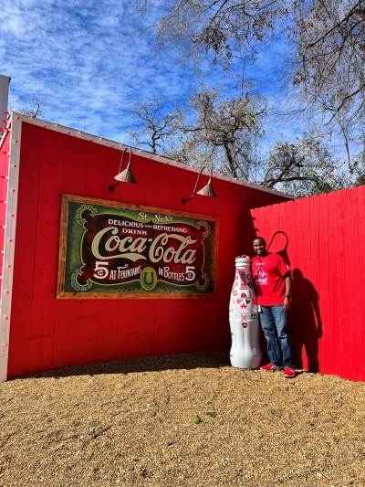 Coca-Cola, then and now...Tyrell Robinson, Sales Execution Manager, with the Recognition Roadtrip Bottle and a vintage Coca-Cola sign at Santa’s Wonderland on Jan. 12, 2022.
