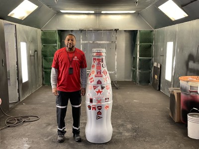 EFC hero, Alrencia Black, Technician, with the Recognition Roadtrip Bottle on Feb. 22, 2022. Fun fact: they are standing in the EFC’s paint booth, where all equipment is pristinely painted before being staged and shipped for distribution.