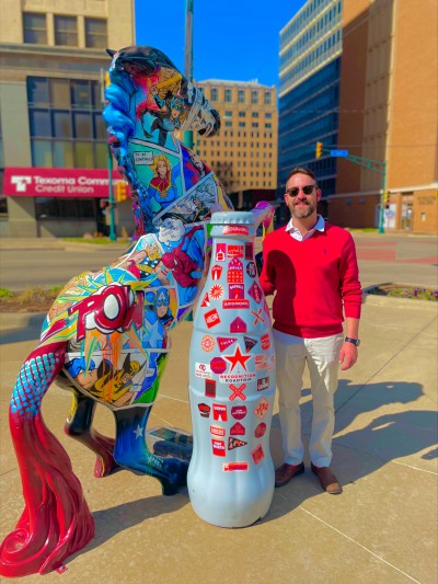 “Whoa there!” Wichita Falls hero Janson Swartz, Order Replenishment Manager, works with the Recognition Roadtrip Bottle to tame the “Choose Your Side” painted horse on March 28, 2022. The horse, which depicts superheroes and villains, was painted by artist Amy Walker in 2017 and is owned today by the Downtown Lion’s Club.